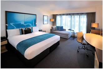 A bedroom with a bed and desk in a room Description generated with very high confidence